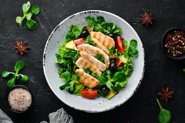 Фото Салат с куриным филе, оливками, помидорами и авокадо в тарелке на деревянном фоне вид сверху свободное место для текста плоская планировка