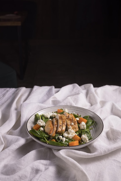 Salad with chicken fillet and spinach on a light fabric background