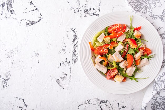 Salad with chicken fillet on a white plate