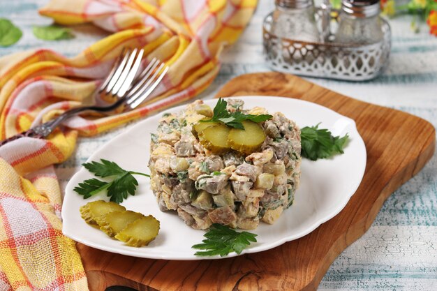 Salad with chicken liver, omelette and pickled cucumbers on white plate, Horizontal format