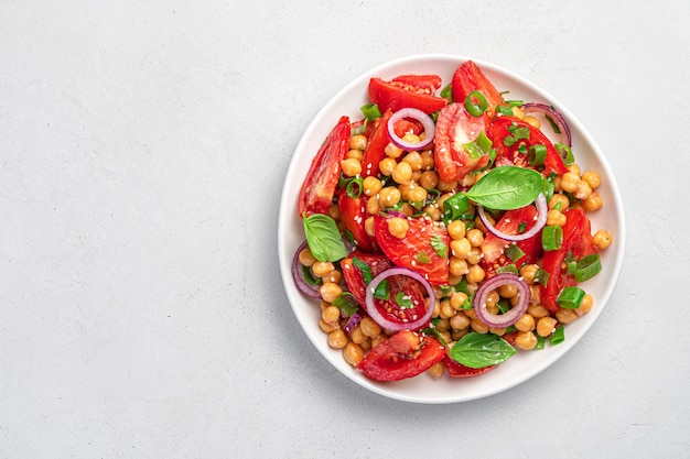 Salad with chickpeas and tomatoes on a gray background. Dietary, healthy, vegetarian food. Top view, copy space