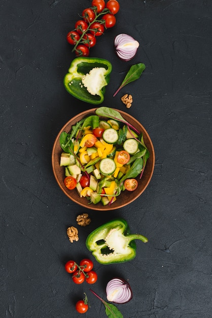 Salad with colorful vegetables on black kitchen counter