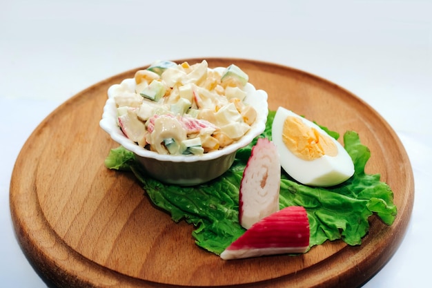 Salad with crab sticks cubed cucumber corn and egg with mayonnaise on a board