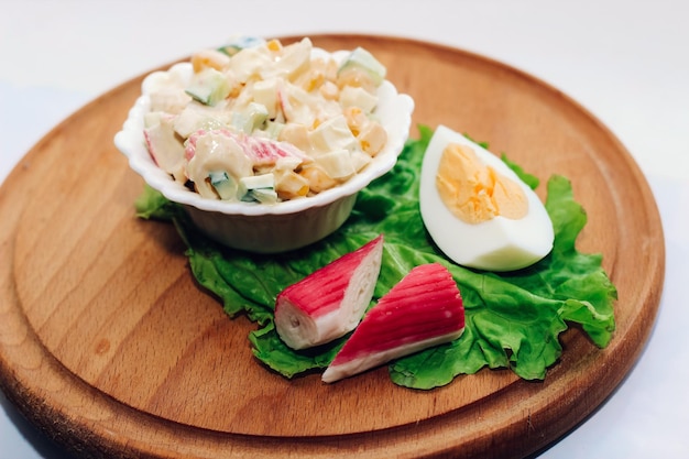 Salad with crab sticks cubed cucumber corn and egg with mayonnaise on a board