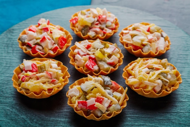 Salad with crab in tartlets on a black board laid out in a circle.