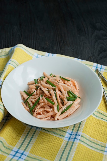 Insalata con ravanello daikon, cipolle verdi, miele e peperoncino rosso in polvere. insalata asiatica. disteso.