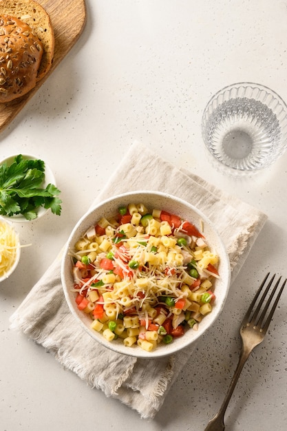 Salad with ditalini pasta, peas, vegan sausage on modern white table. Close up.