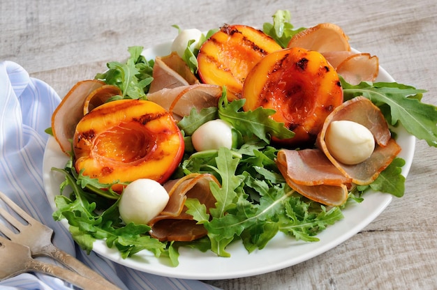 Salad with dried ham, grilled nectarine, mozzarella and arugula