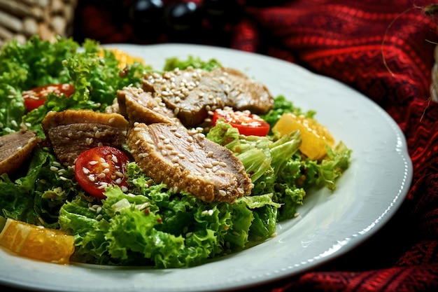 Salad with duck breast tomatoes and sauce in a white plate