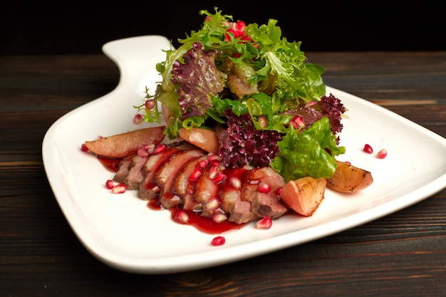 Salad with duck brisket suvid on a wooden table