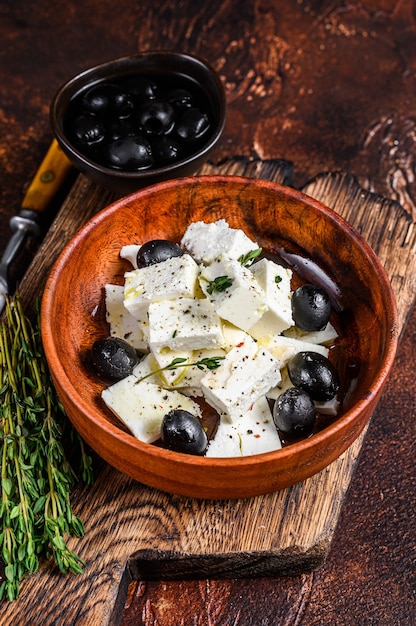 Salad with fresh feta cheese, thyme and olives. Dark background.