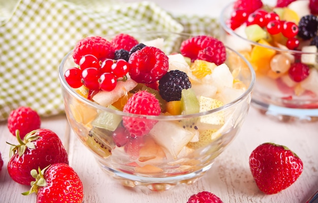 Salad with fresh fruits and berries on a bowls on the white background