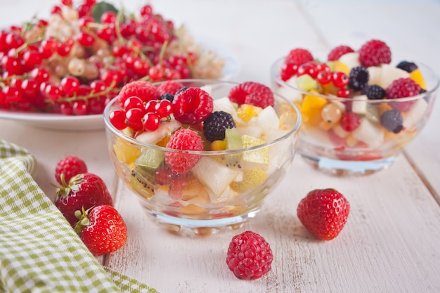 Salad with fresh fruits and berries on a bowls on the white background