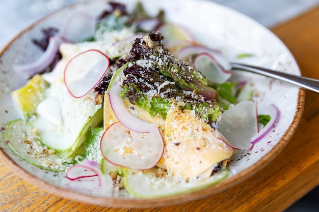 Salad with fresh herbs, radishes and cheese on a plate.