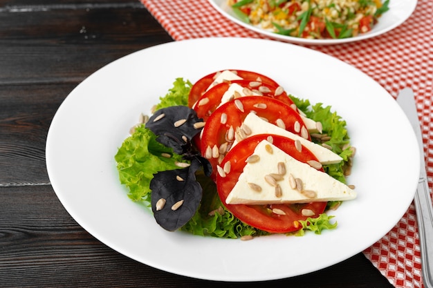 Salad with fresh tomatoes and brined cheese, sunflower seeds on top close up