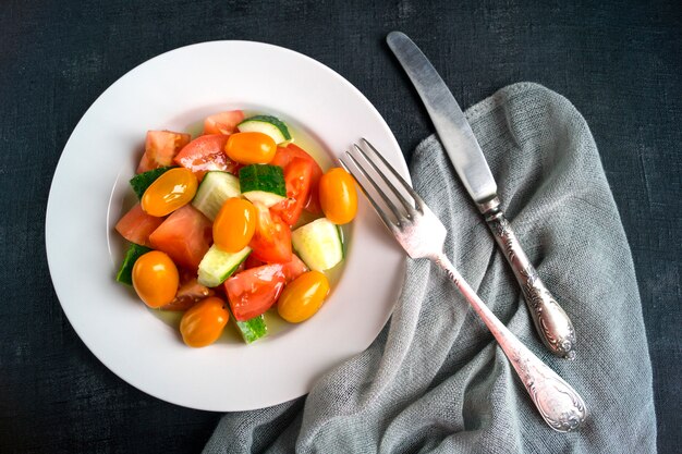 Salad with fresh vegetables on black background