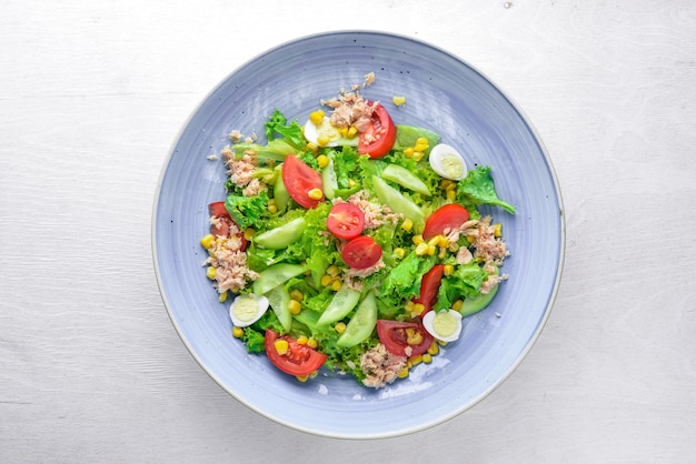 Salad with fresh vegetables and tuna On a wooden background Top view Free space for your text