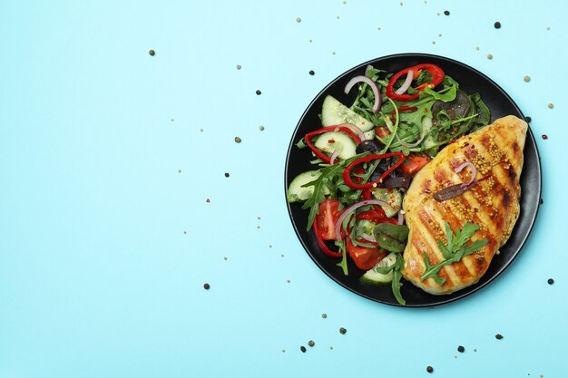 Salad with grilled chicken on blue background