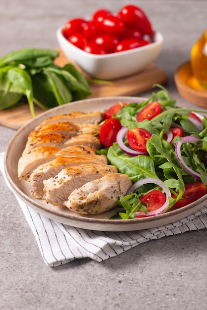Салат с курицей-гриль, свежими овощами, шпинатом, рукколой, красным луком и помидорами.
