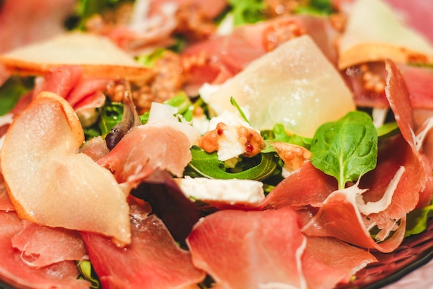 Salad with herbs arugula prosciutto cheese green olives and nuts