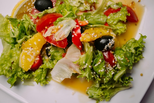 Salad with iceberg lettuce olives tomatoes chicken pineapple slices and sesame seeds