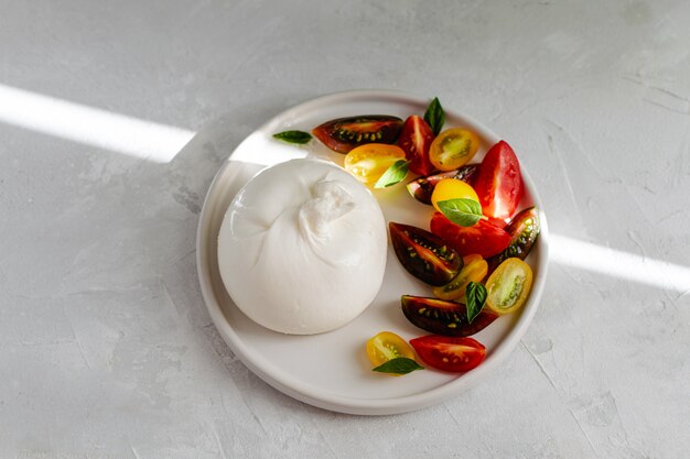 Salad with italian burrata cheese, fresh ripe tomatoes and basil