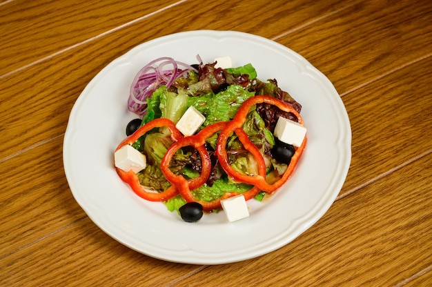 Insalata con lattuga, pepe e parmigiano su fondo in legno