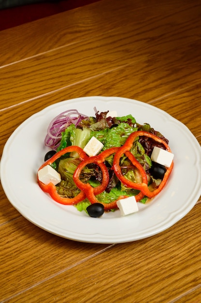 Salad with lettuce, pepper and parmesan cheese on wooden background