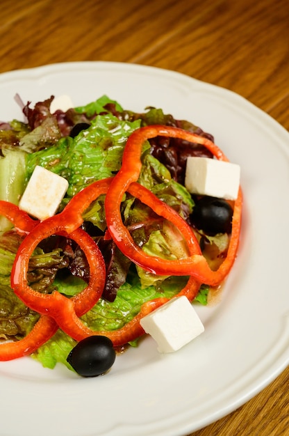 Salad with lettuce, pepper and parmesan cheese on wooden background