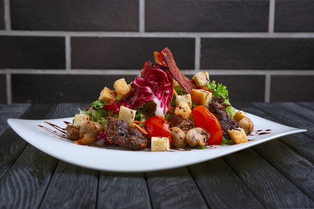 Salad with liver, bacon, grilled tomato and pepper with red cabbage and mushrooms