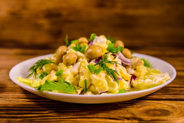 Salad with marinated mushrooms, eggs, red onion, boiled potato and mayonnaise on rustic wooden table