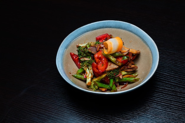 Salad with meat and vegetables on a black background