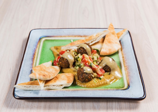 가벼운 나무 테이블에 사각형 접시에 고기와 야채 샐러드. 건강에 좋은 음식
