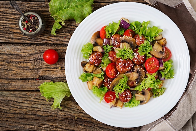 Salad with meatballs, eggplant, mushrooms and tomatoes in Asian style.