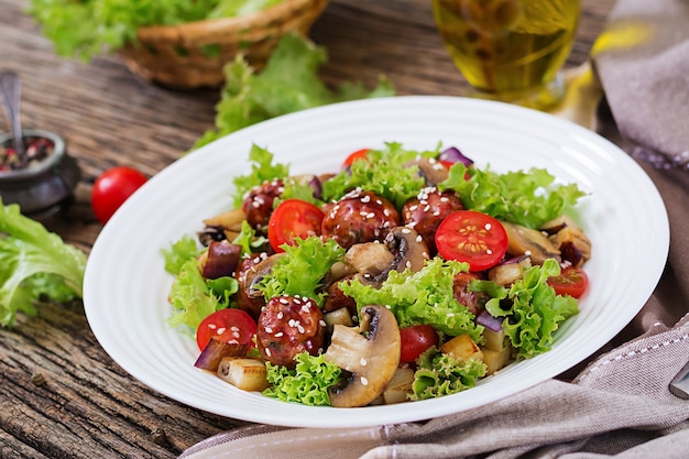 Salad with meatballs, eggplant, mushrooms and tomatoes in Asian style.