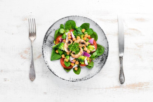 Salad with mushrooms spinach Turkish peas and onion in a plate on a wooden background Top view Free space for your text Flat lay