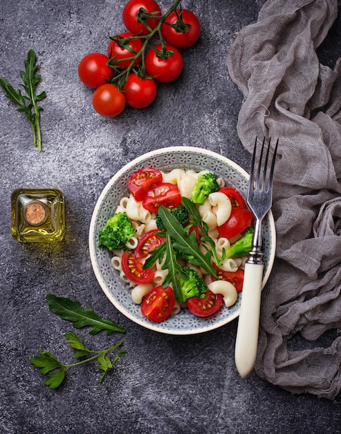 Salad with pasta, cherry tomatoes, broccoli and arugula. Vegan food