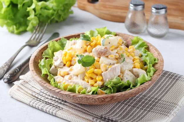 Photo salad with pineapple, baked chicken and corn on a plate of coconut, closeup. horizontal format