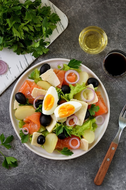 Salad with potatoes, salted salmon, black olives, red onions, parmesan, and lettuce