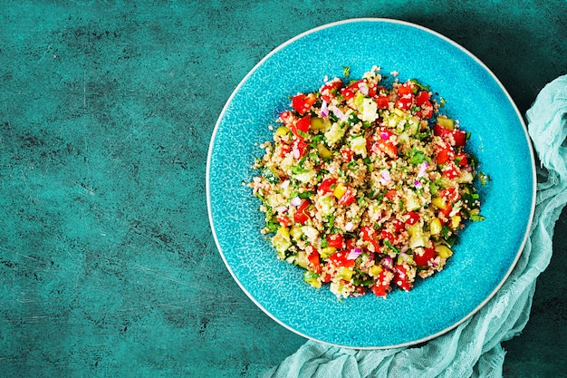 Salad with quinoa, arugula, sweet peppers, tomatoes and cucumber in bowl. Healthy food, diet, detox and vegetarian concept. Tabbouleh salad. Top view. Flat lay