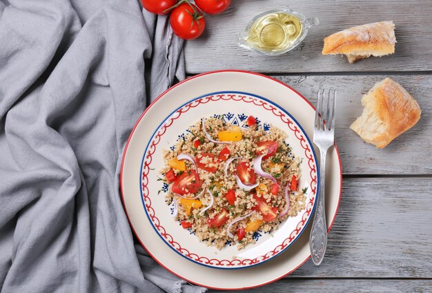 Salad with quinoa tomatoes and onion served on grey wooden background