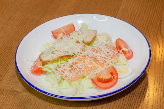 Salad with red fish, eggs and tomatoes, sprinkled with cheese