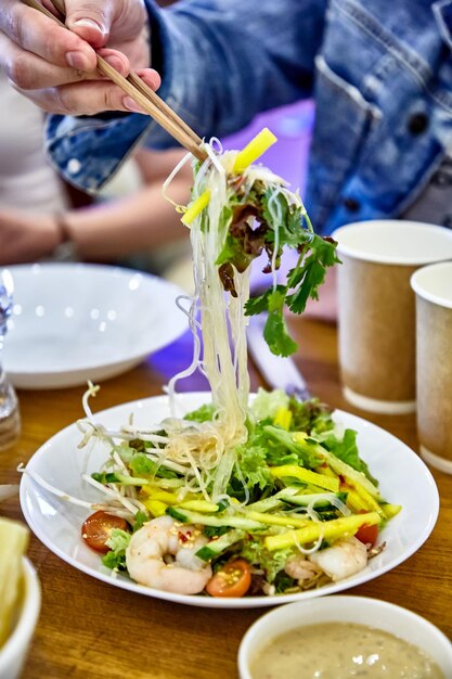 Salad with rice noodles shrimp avocado in Asian style is on the plate