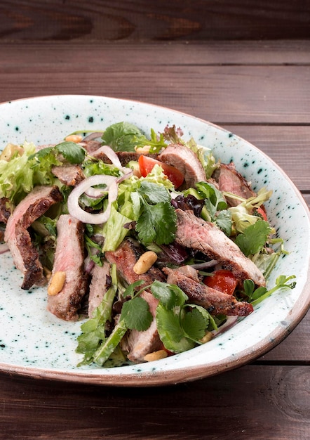 Salad with roast beef and cherry tomatoes on a wooden background