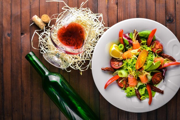 Salad with salmon and fresh vegetables and herbs Italian cuisine Top view On Wooden background