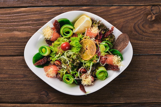 Salad with salted salmon cheese and salad leaves On a wooden surface Top view Free space for your text