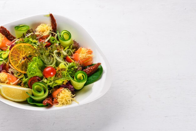 Salad with salted salmon cheese and salad leaves On a wooden surface Top view Free space for your text