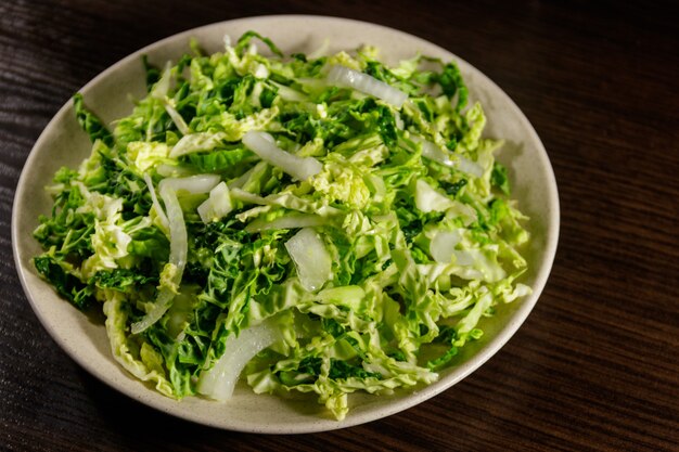 Salad with savoy cabbage and onion on wooden table