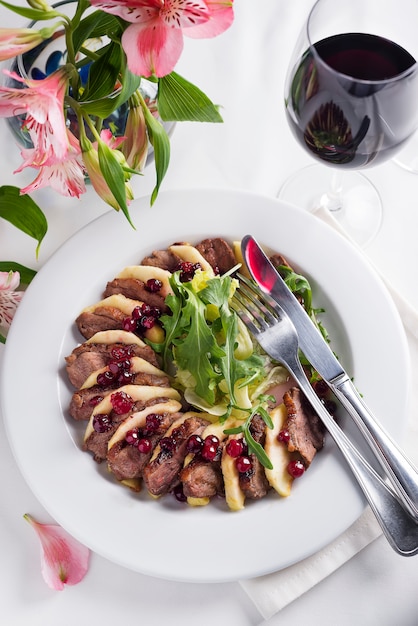 Salad with slices of duck breast with apples and salad under cowberry sauce