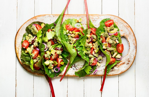Salad with tomato,avocado,garlic sauce in chard leaves.Summer vitamin salad on kitchen board
